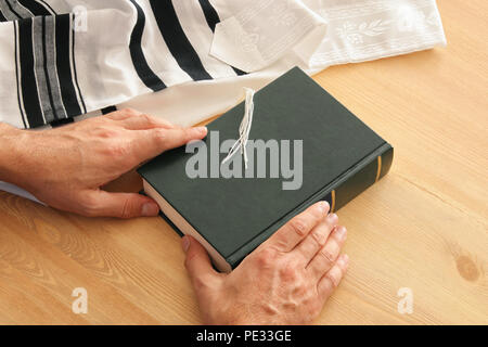 Uomo ebraico mani un libro di preghiere, pregando accanto al tallit. Jewish simboli tradizionali. Rosh hashanah (ebreo nuovo anno di vacanza), Shabbat e Yom Foto Stock