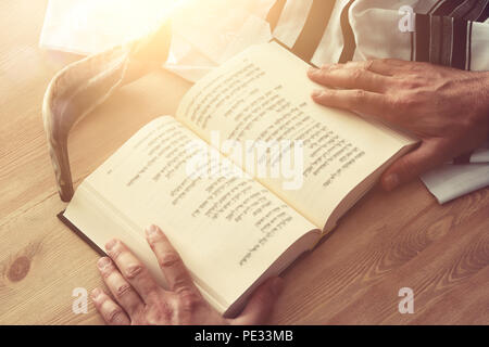 Uomo ebraico mani un libro di preghiere, pregando accanto al tallit. Jewish simboli tradizionali. Rosh hashanah (ebreo nuovo anno di vacanza), Shabbat e Yom Foto Stock