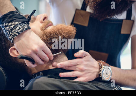 Close-up della mano di un barbiere con le forbici durante la rifinitura Foto Stock