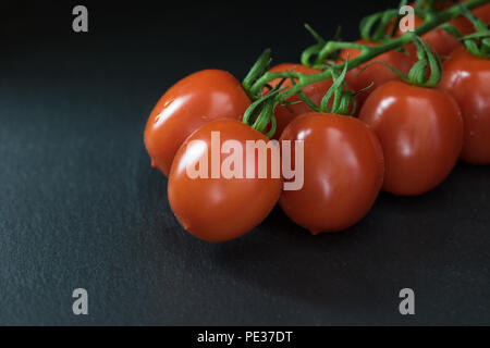 Tasto basso shot con un mezzo di arbusti pomodori giacente sulla pietra nera tabella. Non vi è posto per il testo sulla foto. Foto Stock