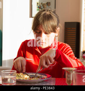 Ragazza di dodici anni per mangiare in una tabella Foto Stock