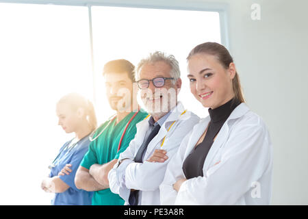 Un gruppo di medici stanno utilizzando una tavoletta digitale per discutere la diagnosi e sorridere mentre in piedi nella parte anteriore del suo paziente. Foto Stock