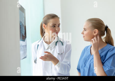 I medici le donne la discussione e la revisione di una risonanza magnetica o di imaging con raggi x controllo film cranio di testa umana nella sala esame. Isolato su bianco Foto Stock