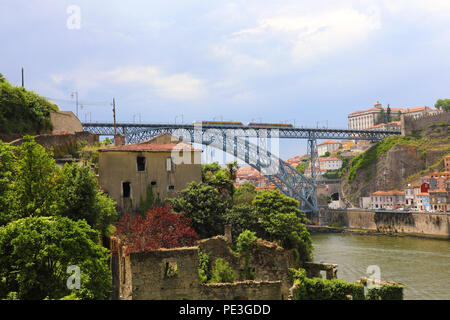 Dom Luis I ponte con il tram che passa e il fiume Douro con vecchi ruderi in primo piano, Porto, Portogallo Foto Stock