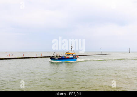 Un piccolo blu barca da pesca restituisce immettendo il fiume Arun estuario a West Beach, Littlehampton, south coast resort per vacanze in West Sussex in estate Foto Stock