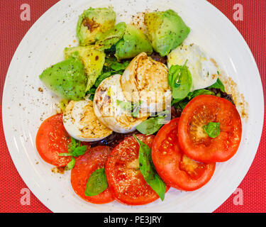 Uno stile di vita sano: tipica dieta mediterranea, Insalata tricolore ingredienti fette di pomodori rossi, bianco mozzarella di bufala Formaggi e verde avocado pera Foto Stock