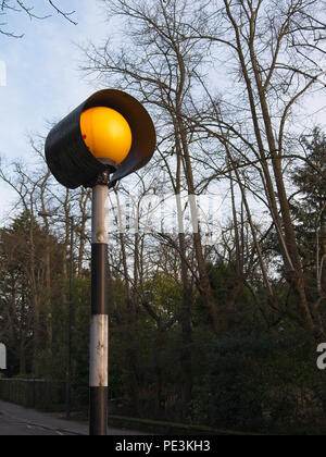 Belisha beacon in cima al suo polo a righe. Color ambra lampada globo sulla cima di un alto in bianco e nero la pole, la marcatura di attraversamenti pedonali delle strade. Foto Stock