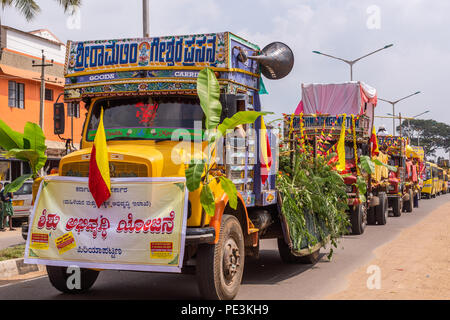 Mellahalli, Karnataka, India - 1 Novembre 2013: Karnataka Rajyotsava Parade. La linea di pesanti corlorfully decorate camion. Banner racconta la nuova G Foto Stock