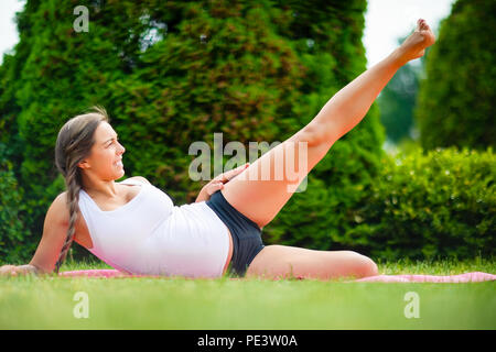 Donna in attesa di eseguire la reclinazione lato sollevamento gamba sul materassino yoga Foto Stock