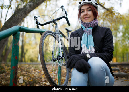 Immagine di bruna seduti sulle scale accanto alla bicicletta Foto Stock