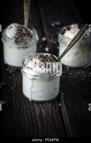 Gelato alla crema con biscotti al cioccolato in vasetti di vetro. Rustico scrivania in legno. Foto Stock