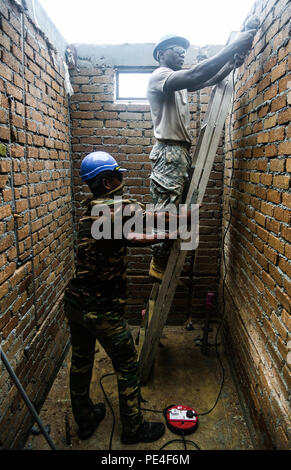 Stati Uniti Army Spc. Chris Dobbins, Louisiana National Guardsman plummer dall Ingegnere 1020th Company, intagliano scanalature in mattoni con una smerigliatrice a intarsio di tubazioni in PVC mentre Tentera Darat Malaysia Cpl. Azlan Rosli, dal 2° Squadrone tecnico reale reggimento, tiene il suo ultimo durante una scuola costruire al di là di funzionamento Keris sciopero, Pacific Pathways 2015 in Tai Ping, Malaysia, sul Sett. 9, 2015. Funzionamento Keris Strike è una pianificata regolarmente esercizio bilaterale sponsorizzato da U.S. Army-Pacific, ospitato annualmente dal Tentera Darat Malaysia a promuovere la sicurezza regionale, il sostegno e la cooperazione. (U.S. Foto dell'esercito Foto Stock