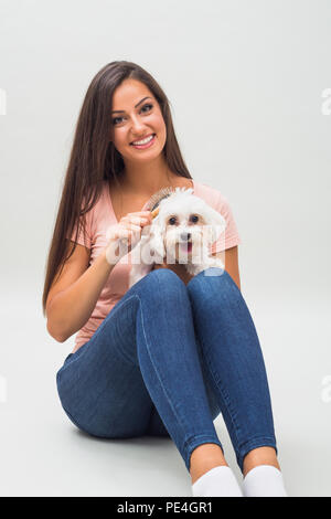 Felice femmina cane maltese è la pettinatura bella giovane donna. Foto Stock