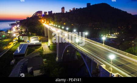 Vista Drone dell'illuminato Matsesta viadotto e la montagna con una densa foresta al tramonto, Sochi, Russia Foto Stock