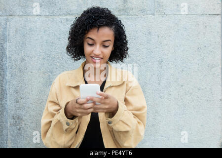 Donna latinoamericana inviando un messaggio con il telefono cellulare all'aperto con spazio di copia Foto Stock