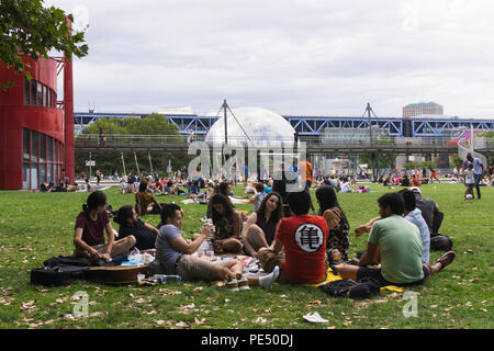 Parco di Parigi - Persone rilassarsi sul prato del La Villette Parco con una vista dello specchio-dome finito La Géode, Parigi, Francia, Foto Stock