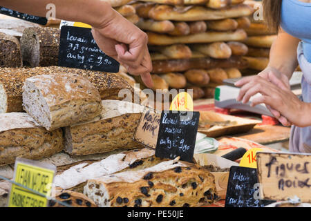 Parigi mercato alimentare - il cliente puntare il dito di un pane venduto su un mercato degli agricoltori a Parigi, in Francia, in Europa. Foto Stock