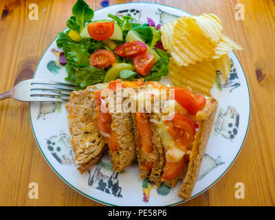 Pranzo in North Yorkshire paese café al formaggio e pomodoro sandwich tostato sul pane marrone con insalata e patatine. Foto Stock