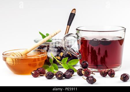 Fatti in casa da tè di rosa canina. Cura tradizionale per raffreddori e influenza. Frutti di bosco essiccati della boccola essiccato su uno sfondo bianco. Calda tè di rosa canina. Tè invernali Foto Stock