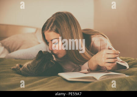 Bella donna la lettura del libro e trascorrere il tempo con il suo gatto.Immagine è intenzionalmente tonica. Foto Stock