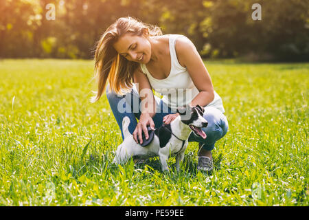 Bella donna la pettinatura il suo cane Jack Russell Terrier nella natura.Immagine è intenzionalmente tonica. Foto Stock