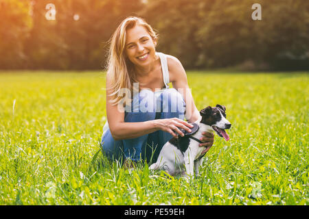 Bella donna la pettinatura il suo cane Jack Russell Terrier nella natura.Immagine è intenzionalmente tonica. Foto Stock