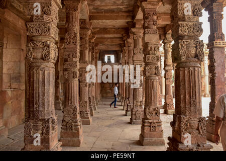 Un uomo cammina tra la serie di colonne Sculputed all'interno Quwwat -ul-Islam moschea al complesso di Qutub a Delhi in India. Qutub Minar in piedi 73 metri alta a Delhi, è il più alto minareto in mattoni e dall'UNESCO patrimonio dell'umanità. Esso rappresenta la indo-islamica stile architettonico, costruito da Qutb-ud-din Aibak come una vittoria Torre nel 1192 D.C. Foto Stock