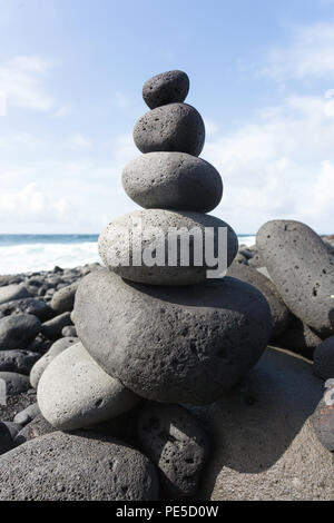 Impilate le pietre o ciottoli su una spiaggia con il blu del cielo in background. Foto Stock