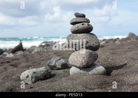 Impilati equilibrata di sassi o ciottoli su una spiaggia di sabbia nera. Foto Stock