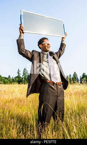 Un giovane hip americano africano imprenditore tenendo un pannello solare fino al sun. Energia verde concetto / Verde il concetto di business Foto Stock