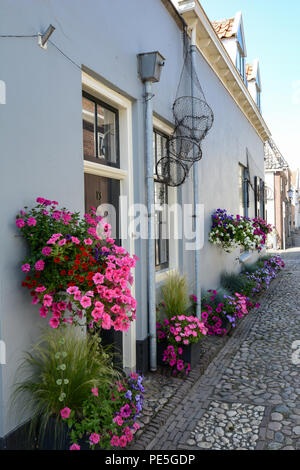 Fiore-decorate antiche strade di ciottoli nel villaggio di Elburg, provincia di Gelderland, Paesi Bassi. Attrazione turistica di fiori d'estate. Foto Stock