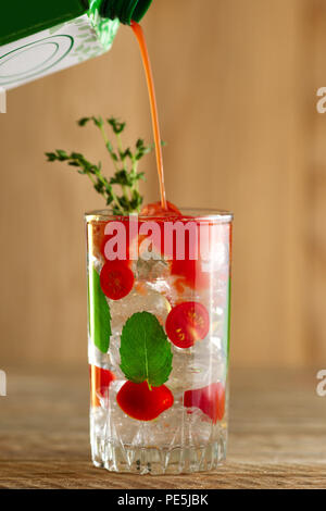 Versare il succo di pomodoro per cocktail con vodka, menta e ghiaccio Foto Stock