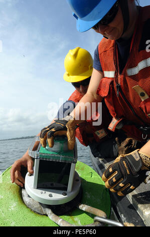 Petty Officer di terza classe Kevin Conklin (sinistra), un macchinario tecnico al Coast Guard ausili alla navigazione Team New York, assiste Fireman Carrie Gillespie come ella attribuisce una luce ad una boa lungo il fiume Navesink in New Jersey, Sett. 29, 2015. Gli uomini e le donne di ANT New York sono responsabili per il mantenimento 480 aiuti primario, 96 aiuti stagionali e 9 grandi fari, aiutando a garantire la sicurezza del trasporto marittimo nella regione. (U.S. Coast Guard foto di Sottufficiali di terza classe Flockerzi Ali). Foto Stock