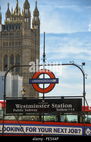Segno sopra la porta di ingresso per la stazione della metropolitana di Westminster a Londra, con un cercando il vostro lavoro successivo messaggio sul lato di un bus rosso in background.