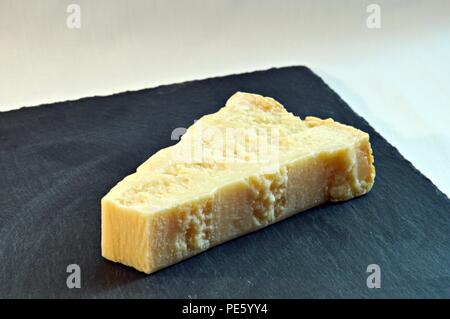 Pezzo di formaggio grana padano su ardesia plain Foto Stock