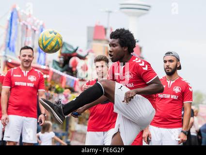 Amburgo, Germania. 13 Ago, 2018. Josef Muftawa (M) e i giocatori di calcio del FC Hamburger Berg dribbling oltre il folk festival "Hamburger Dom'. Dopo due mesi, il club si è conclusa la più lunga di dribbling calcio nel mondo. I giocatori hanno coperto più di 4 mila chilometri con la palla sul loro i piedi, chiaramente superando il vecchio record mondiale di 3,069 chilometri. Credito: Daniel Bockwoldt/dpa/Alamy Live News Foto Stock