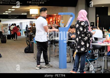 Viaggiatore maschio il riempimento di una bottiglia di acqua in corrispondenza di una stazione di idratazione all'Aeroporto Internazionale di San Francisco, San Francisco, California, Stati Uniti. Foto Stock
