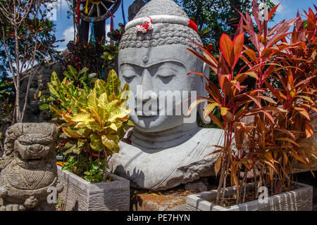 Statua di Pietra del Budda seduto sotto l'albero, con una ghirlanda di bianco e rosso i colori della bandiera indonesiana per Indonesia Giorno Di Indipendenza, Bali, Indones Foto Stock