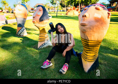 Giovane donna viaggio nel villaggio nascosto di Chiang Mai, scenario outdoor Jurassic park con sculture giganti di dinosauro e altri animali mondo giurassico Foto Stock