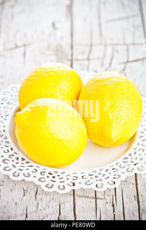 Tre limoni freschi sul rustico sfondo di legno Foto Stock