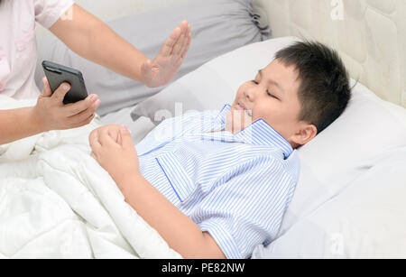 La madre ha ordinato i bambini non giocano con i telefoni cellulari per lungo tempo, problema sul letto, health care concept Foto Stock