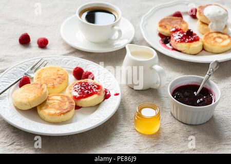 Cottage cheese pancakes con marmellata, miele e panna acida. Syrniki, sirniki. Russo, Ucraino cucina. Una sana colazione gustosa sul tavolo coperti con li Foto Stock