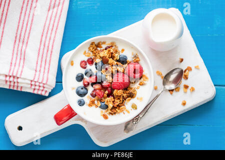 Lo yogurt con i semi di melograno, mirtilli e lamponi e granola. Sana colazione ciotola. Vista superiore Foto Stock