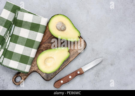 Avocado dimezzato sul tagliere di legno. Vista superiore, copia spazio per il testo Foto Stock