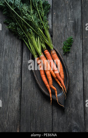 Le carote fresche su un tavolo di legno. Azienda agricola biologica radice raccolto vegetale Foto Stock