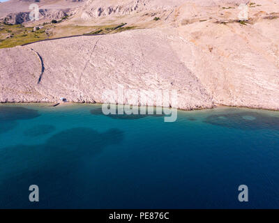 Vista aerea di una tenda alla moda, il coperchio dalla sun. Rocce sul mare e il mare trasparente pavimento. Relax e vacanze sotto una tenda bianca circondata da roccia Foto Stock