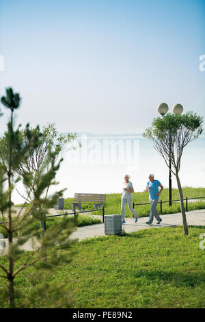 Coppia senior in esecuzione dal lago Foto Stock