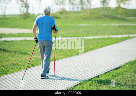 Uomo senior di praticare Nordic Walking vista posteriore Foto Stock