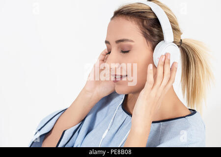 Pretty girl ascolto di musica con cuffie di lei su sfondo bianco Foto Stock