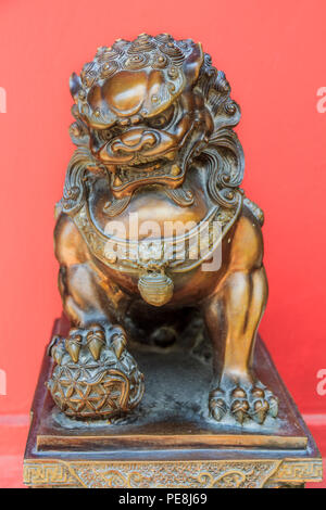 Cinese in bronzo scultura lion, maschio della coppia, tenendo una palla, che rappresenta il mondo nella sua zampa anteriore, simbolo di protezione e potenza in Asia Foto Stock